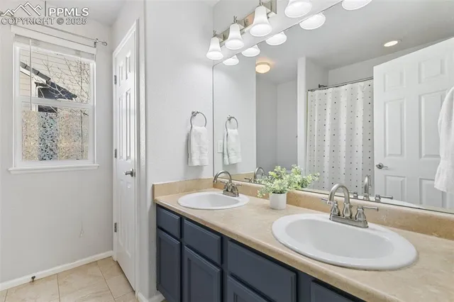 a bathroom with double vanity sinks a vanity a lamp and a mirror