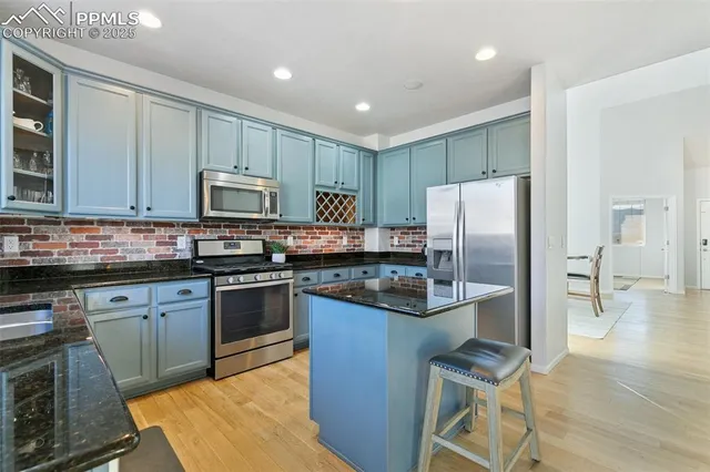 a kitchen with kitchen island granite countertop wooden cabinets and stainless steel appliances