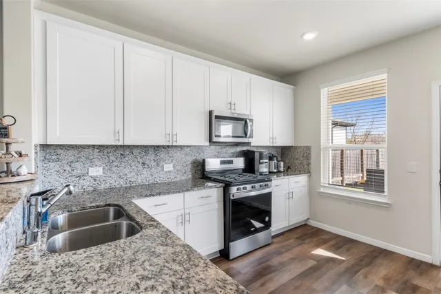 a kitchen with granite countertop a sink wooden floor and a stove top oven