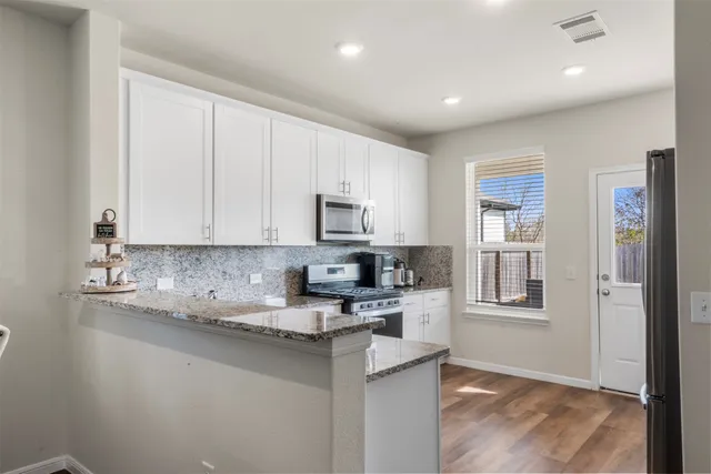 a kitchen with granite countertop white cabinets and stainless steel appliances
