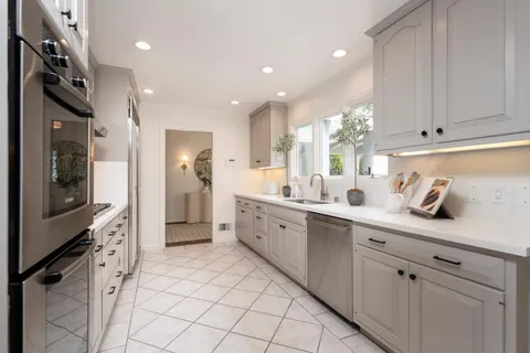 a large white kitchen with a sink stainless steel appliances and cabinets