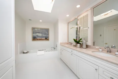 a spacious bathroom with a double vanity sink a mirror and a bathtub