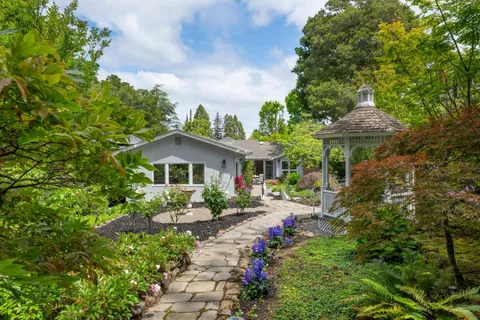 a backyard of a house with table and chairs under an umbrella