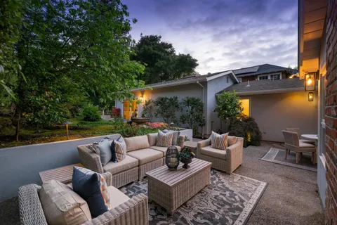 a view of a patio with couches chairs and a floor to ceiling window next to a yard