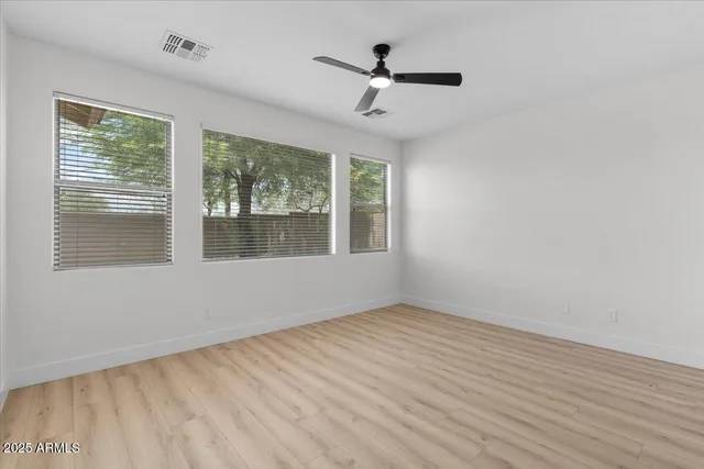 a view of empty room with wooden floor and fan