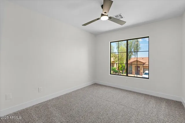 an empty room with windows and fan