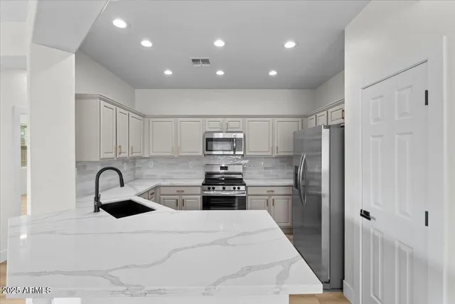 a kitchen with kitchen island stainless steel appliances sink refrigerator and stove