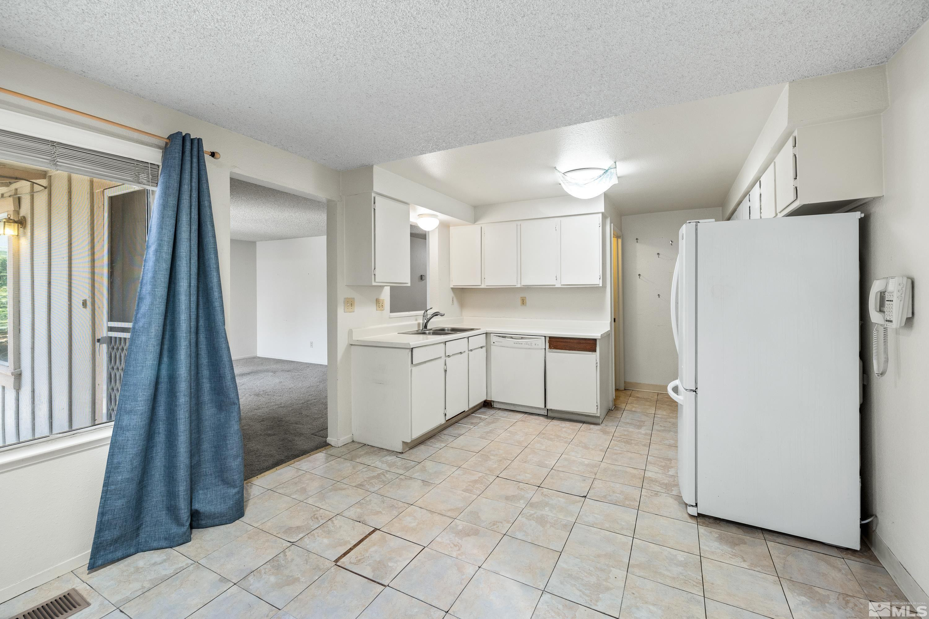 6827 Flower Street Reno, NV 89506 - Photo 13 of 31 a kitchen with white cabinets a sink appliances and a window