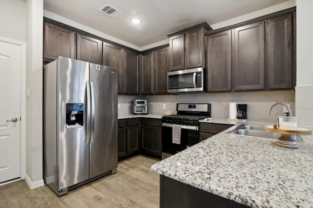 a kitchen with stainless steel appliances granite countertop refrigerator stove microwave and sink
