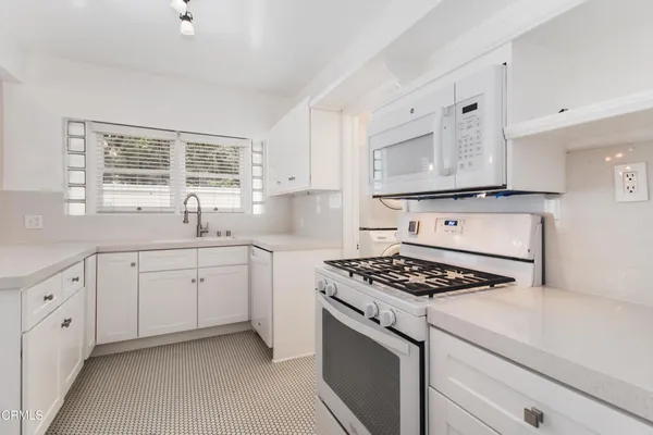 a kitchen with white cabinets stove and sink