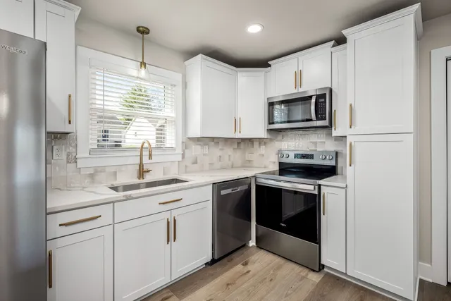 a kitchen with stainless steel appliances granite countertop a sink a stove a refrigerator cabinets and a window