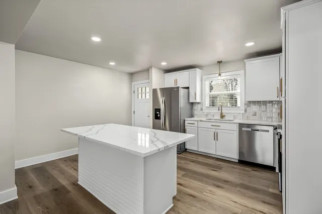 a kitchen with a sink a refrigerator and white cabinets