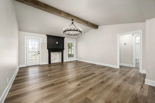 a view of an empty room with wooden floor and windows