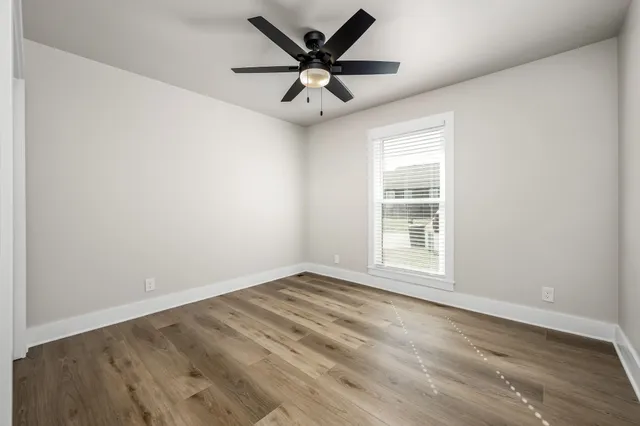 an empty room with window and ceiling fan