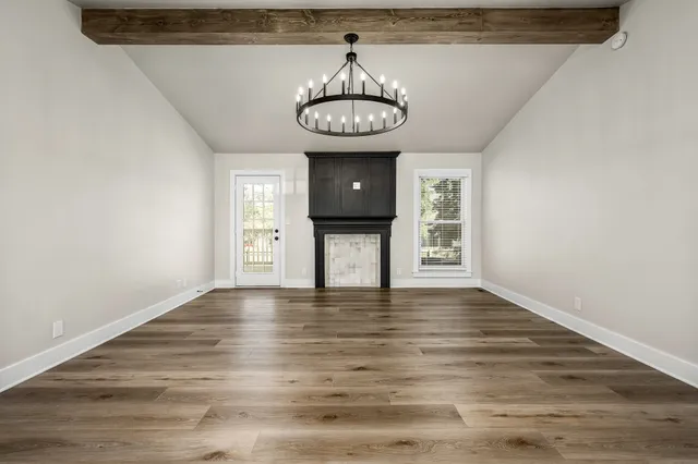 a view of an empty room with window and wooden floor