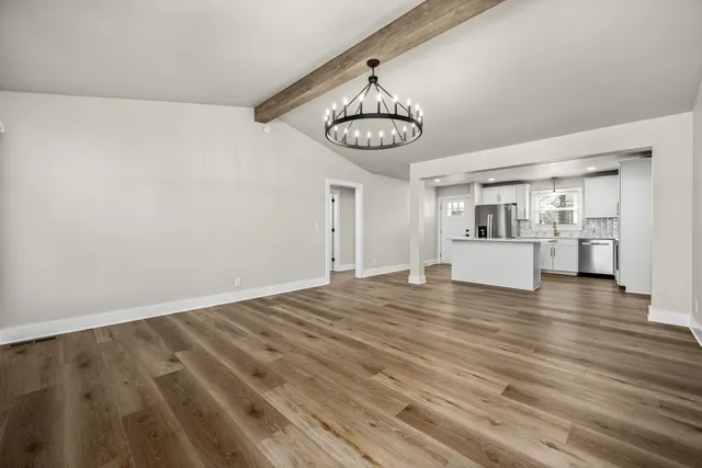 a view of a room with wooden floor and kitchen view