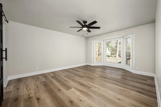 a view of empty room with wooden floor and fan