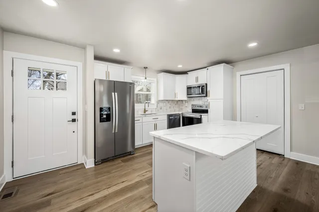 a kitchen with a refrigerator a sink and a stove top oven with wooden floor
