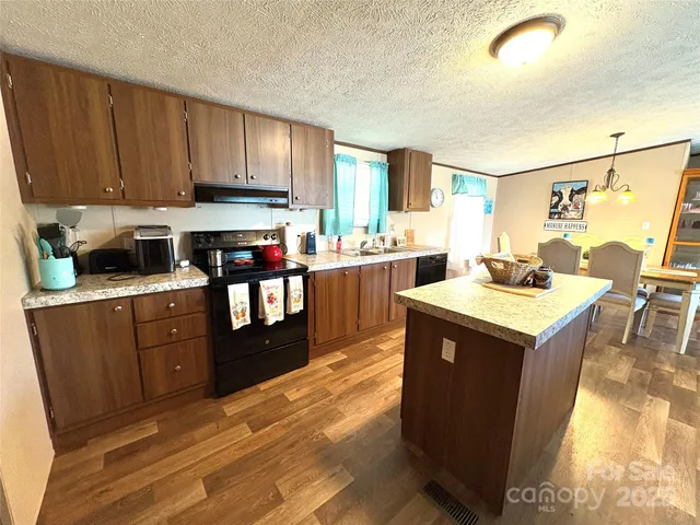 a kitchen with a stove top oven a sink dishwasher and a refrigerator with wooden cabinets