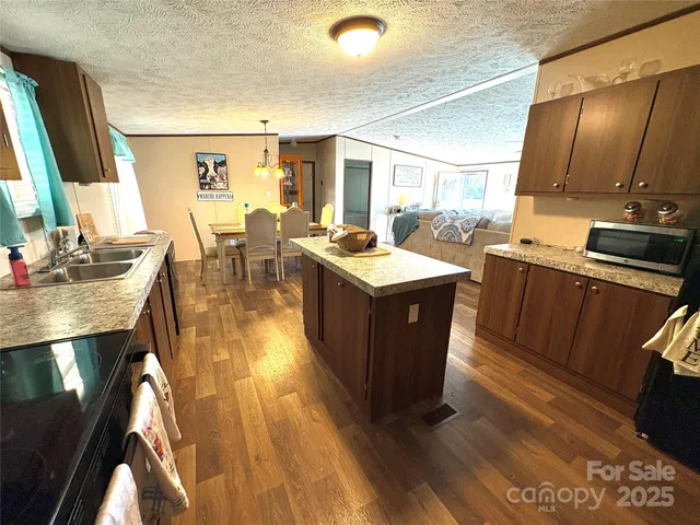 a open kitchen with stainless steel appliances granite countertop a sink dishwasher stove refrigerator and cabinets with wooden floor