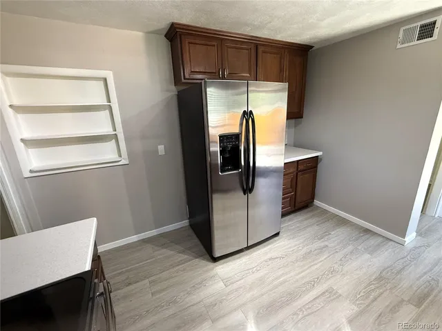a kitchen with stainless steel appliances a refrigerator and wooden floor