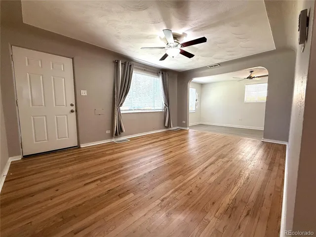 a view of empty room with wooden floor and fan