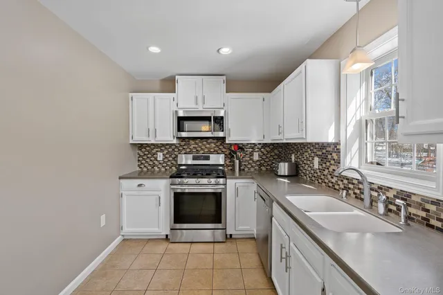 a kitchen with white cabinets appliances and a sink