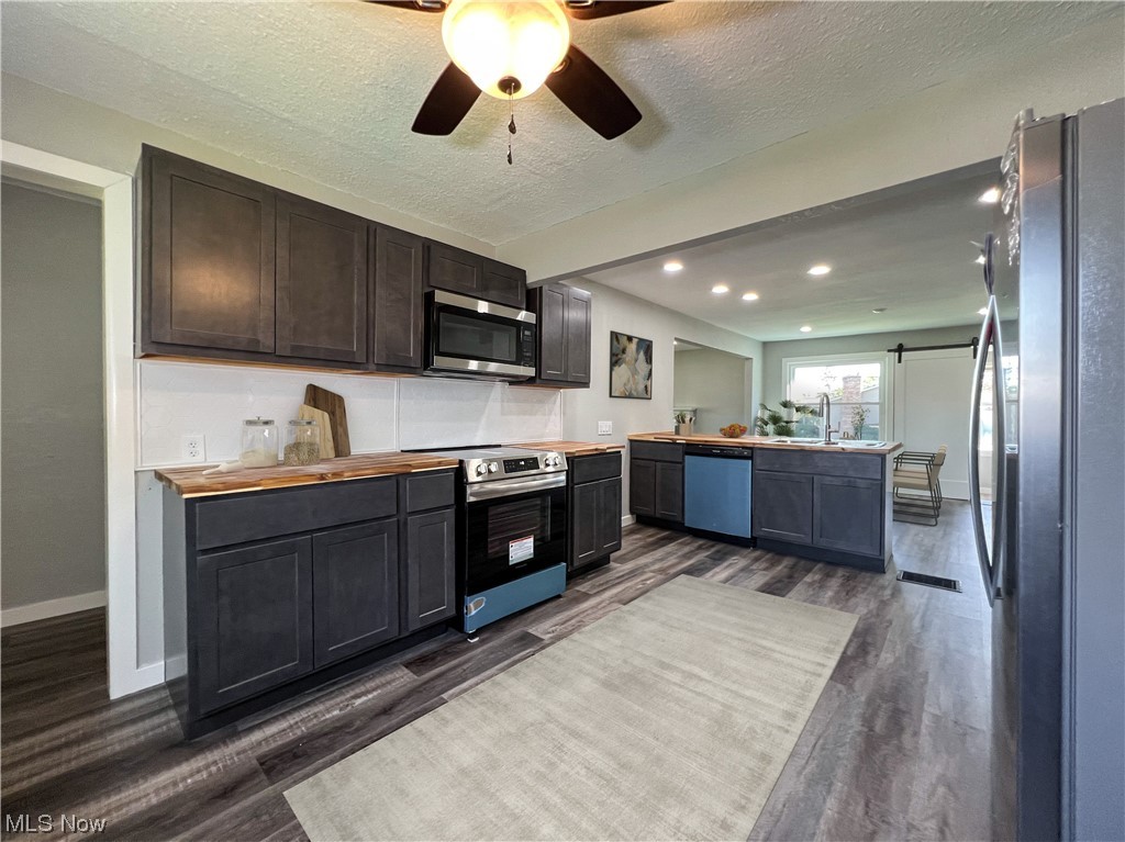 602 West Marshall Road McDonald, OH 44437 - Photo 5 of 19 Kitchen with butcher block counters, ceiling fan, a textured ceiling, dark hardwood floors, and appliances with stainless steel finishes