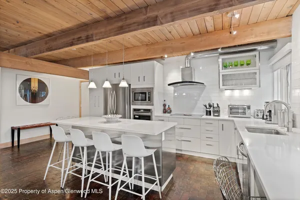 a kitchen with stainless steel appliances kitchen island granite countertop a table chairs and a refrigerator