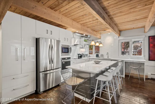 a kitchen with stainless steel appliances a refrigerator a stove a sink dishwasher and white cabinets with wooden floor