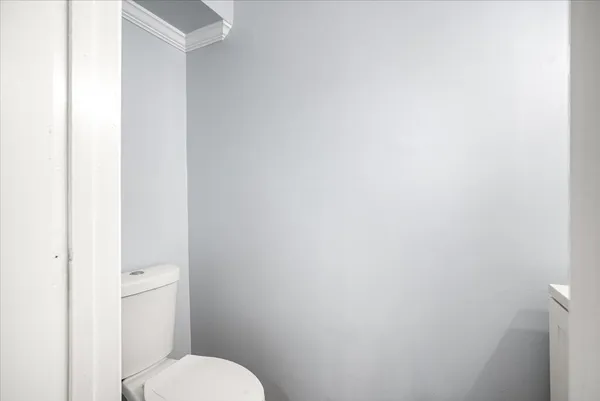 a white toilet sitting next to a white wall