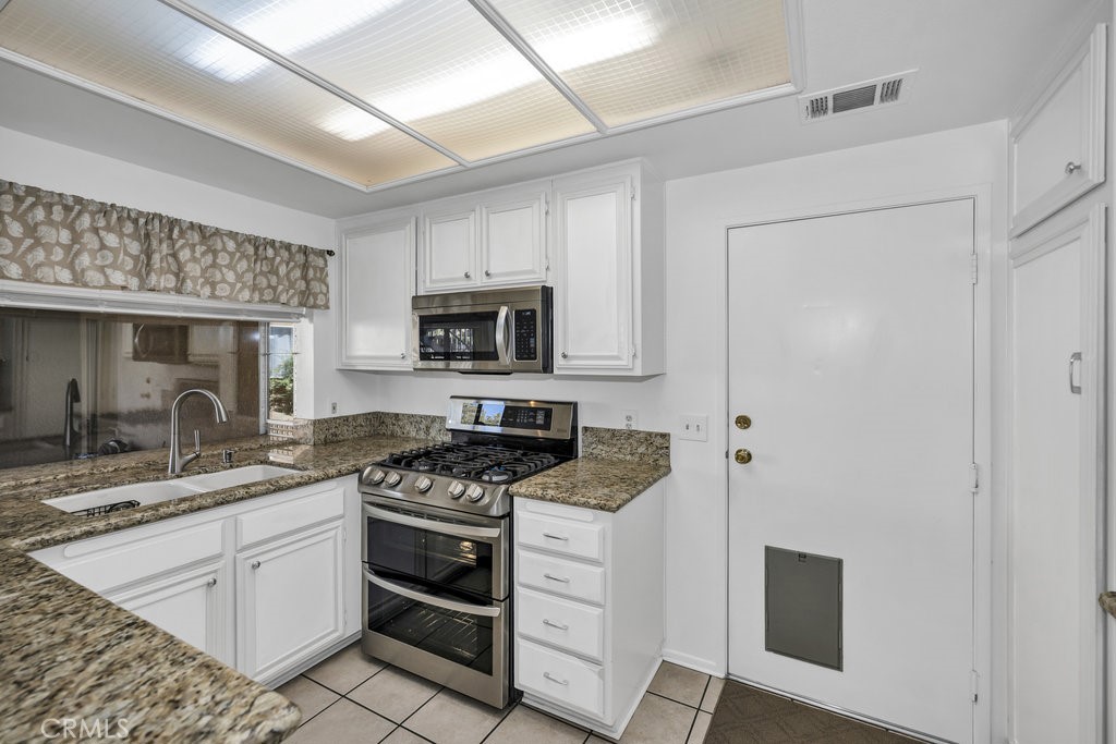 28114 Seco Canyon Road, Unit 156 Saugus, CA 91390 - Photo 10 of 31 a kitchen with white cabinets stainless steel appliances and a counter space