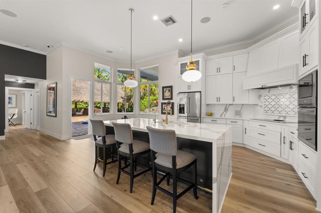 10171 Northwest 59th Drive Parkland, FL 33076 - Photo 3 of 49 a kitchen with stainless steel appliances kitchen island granite countertop a table chairs and a sink