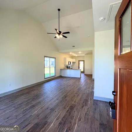 a view of empty room with wooden floor and ceiling fan