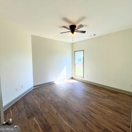 a view of empty room with wooden floor and fan