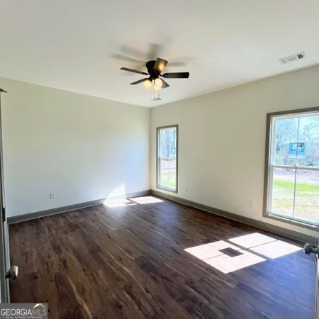 an empty room with wooden floor ceiling fan and windows