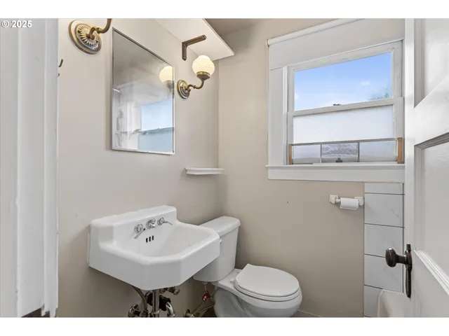a bathroom with a sink a mirror a toilet and a window