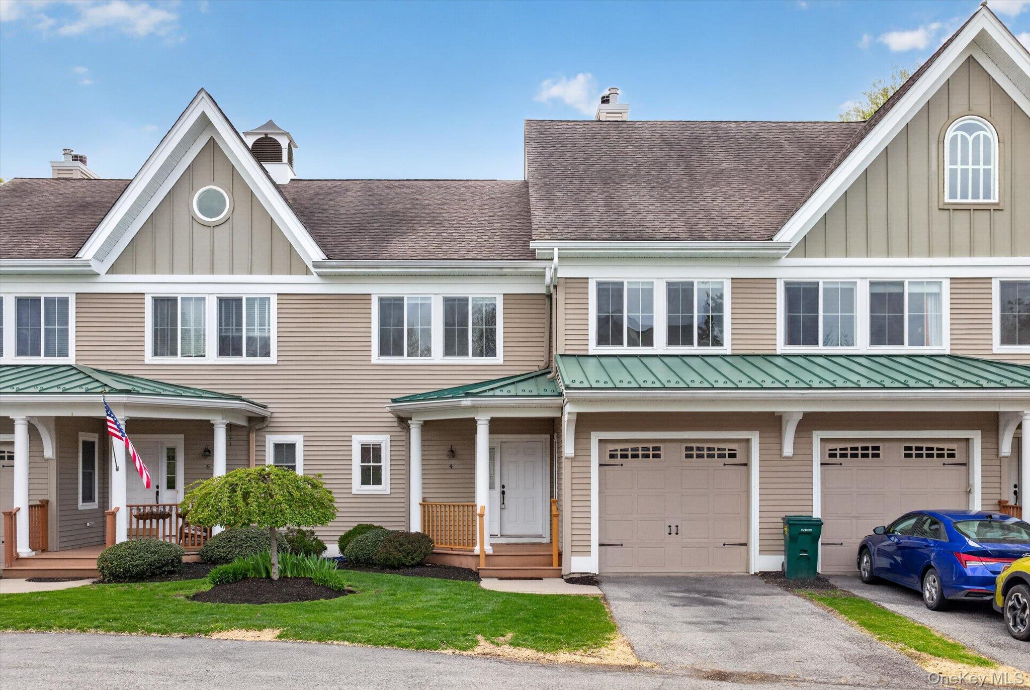 Townhome exterior featuring tan siding, a brown shingle roof, and green metal accent roofing