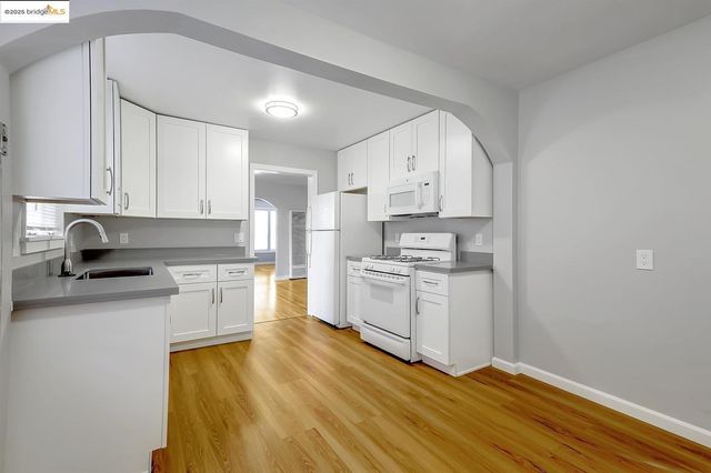 a kitchen with granite countertop white cabinets and white appliances