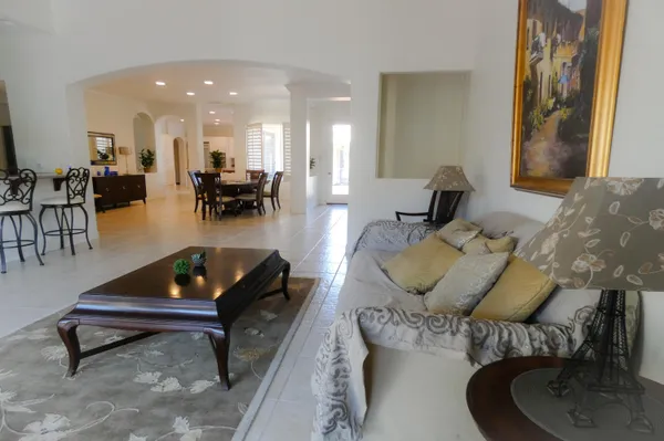 a living room with furniture and a dining table with kitchen appliances