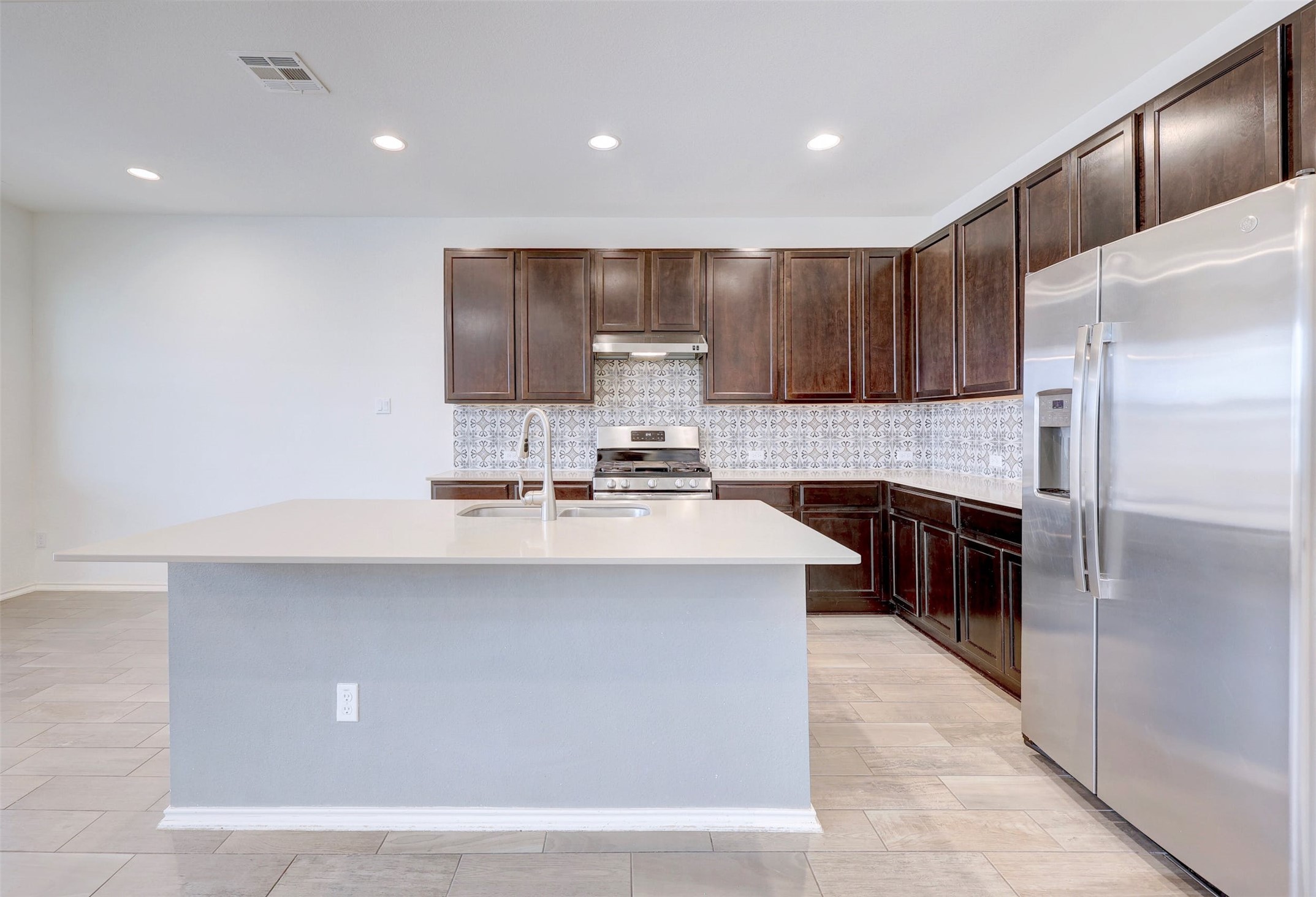 307 Simmental Loop Hutto, TX 78634 - Photo 10 of 34 A contemporary kitchen features dark cabinetry, stainless steel appliances, and a central island with a sink.