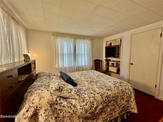 a bedroom with a bed a flat tv screen and a dresser