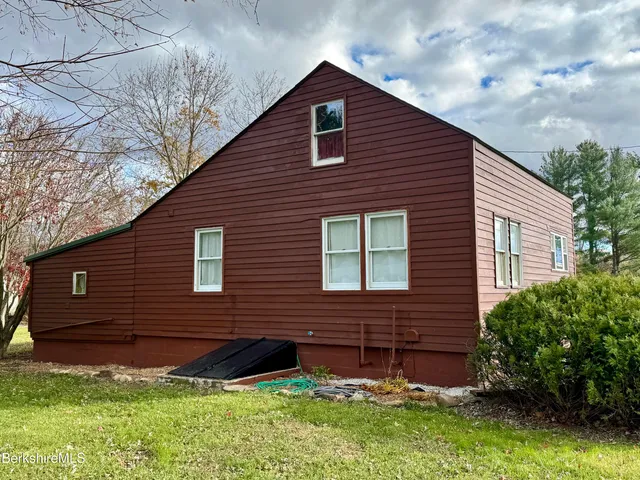 a brick house with a small yard plants and large trees