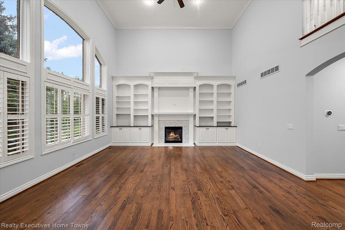 2919 North Addison Circle Rochester, MI 48306 - Photo 20 of 69 Two-story living area with wood-finish flooring, a built-in fireplace, custom built-in shelving, and plantation shutters