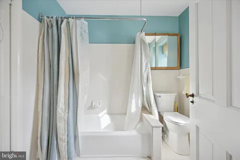 a white toilet sitting next to a bathroom sink and tub