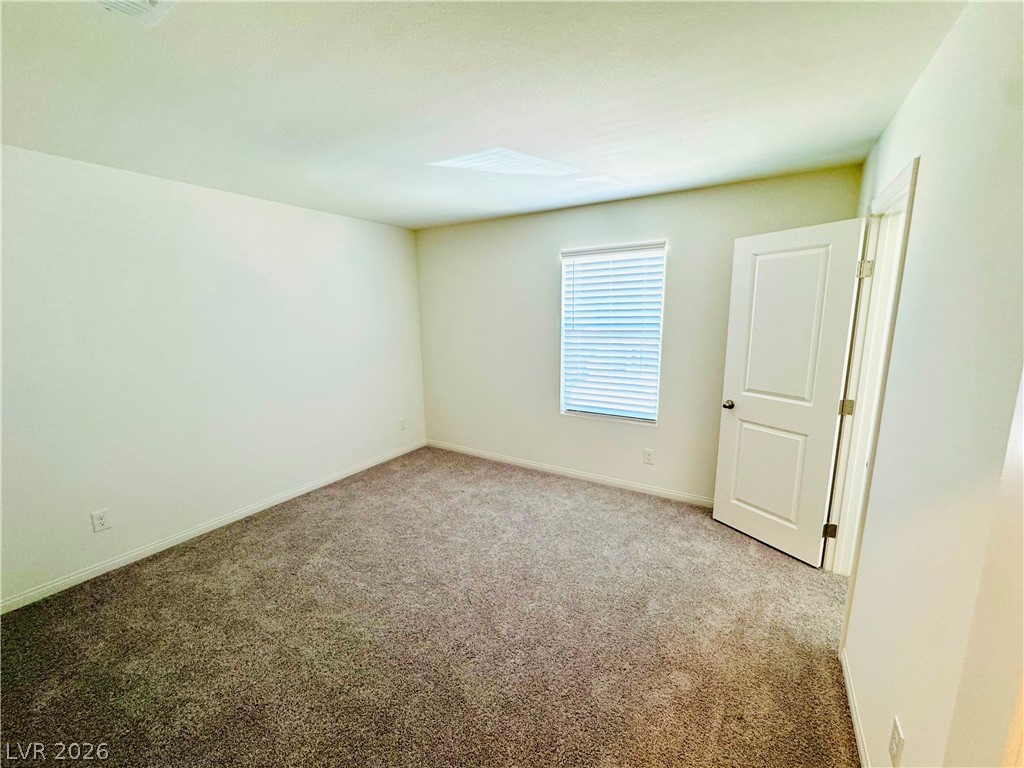 9249 Innot Avenue Las Vegas, NV 89148 - Photo 19 of 24 A well-lit bedroom offering soft carpet flooring and a neutral color palette.
