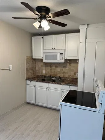 a kitchen with stainless steel appliances a sink a stove a refrigerator cabinets and wooden floor