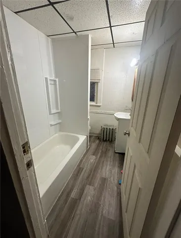 a bathroom with a tub a sink and wooden floor
