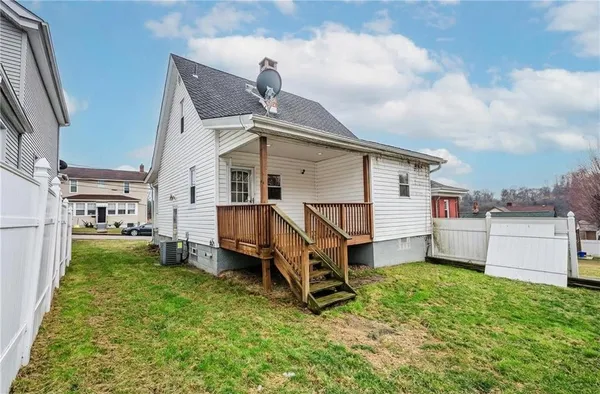 a white house that has a small yard and couches chairs with wooden fence