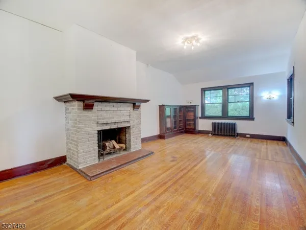 a view of empty room with wooden floor and fireplace